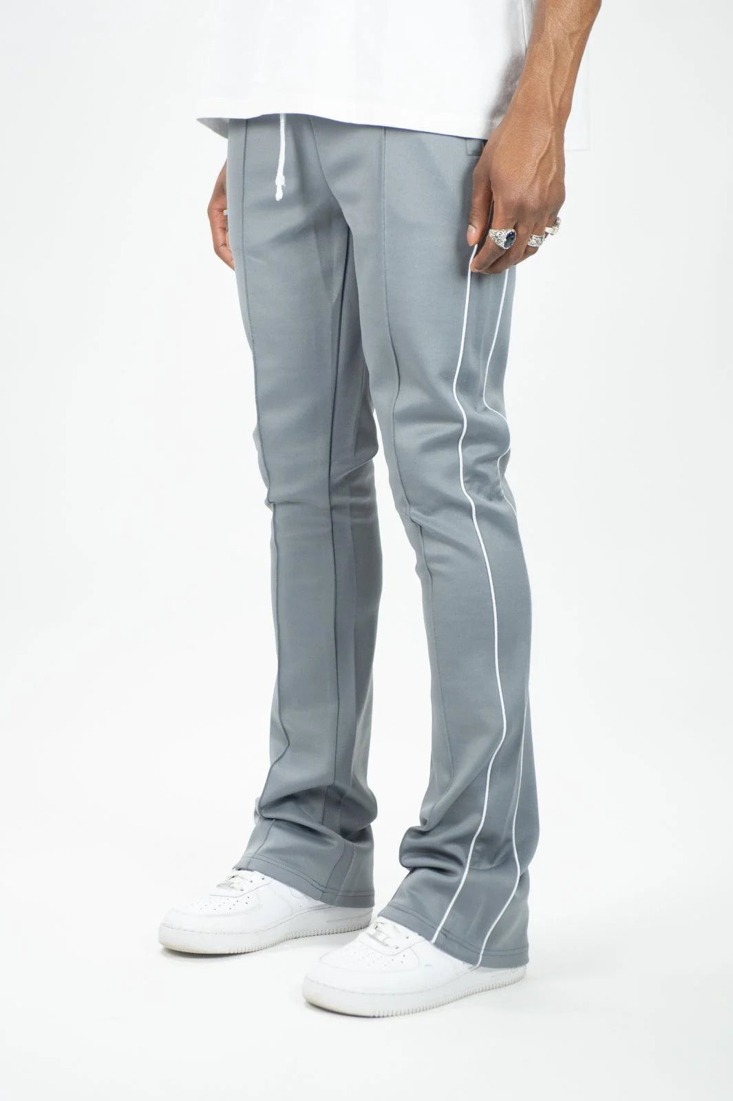 Man wearing Rebel Minds grey stacked fit track pants with white side stripes and white sneakers.