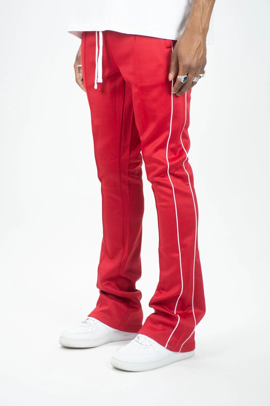Man wearing red Rebel Minds stacked fit track pants with white side stripes and white sneakers.